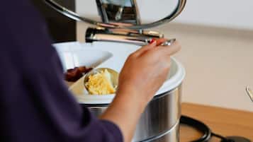A person opening a stainless steel food container with a lid.