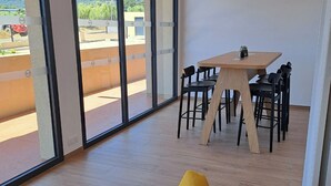 Um interior moderno com janelas amplas, uma mesa de madeira com cadeiras e uma cadeira amarela.