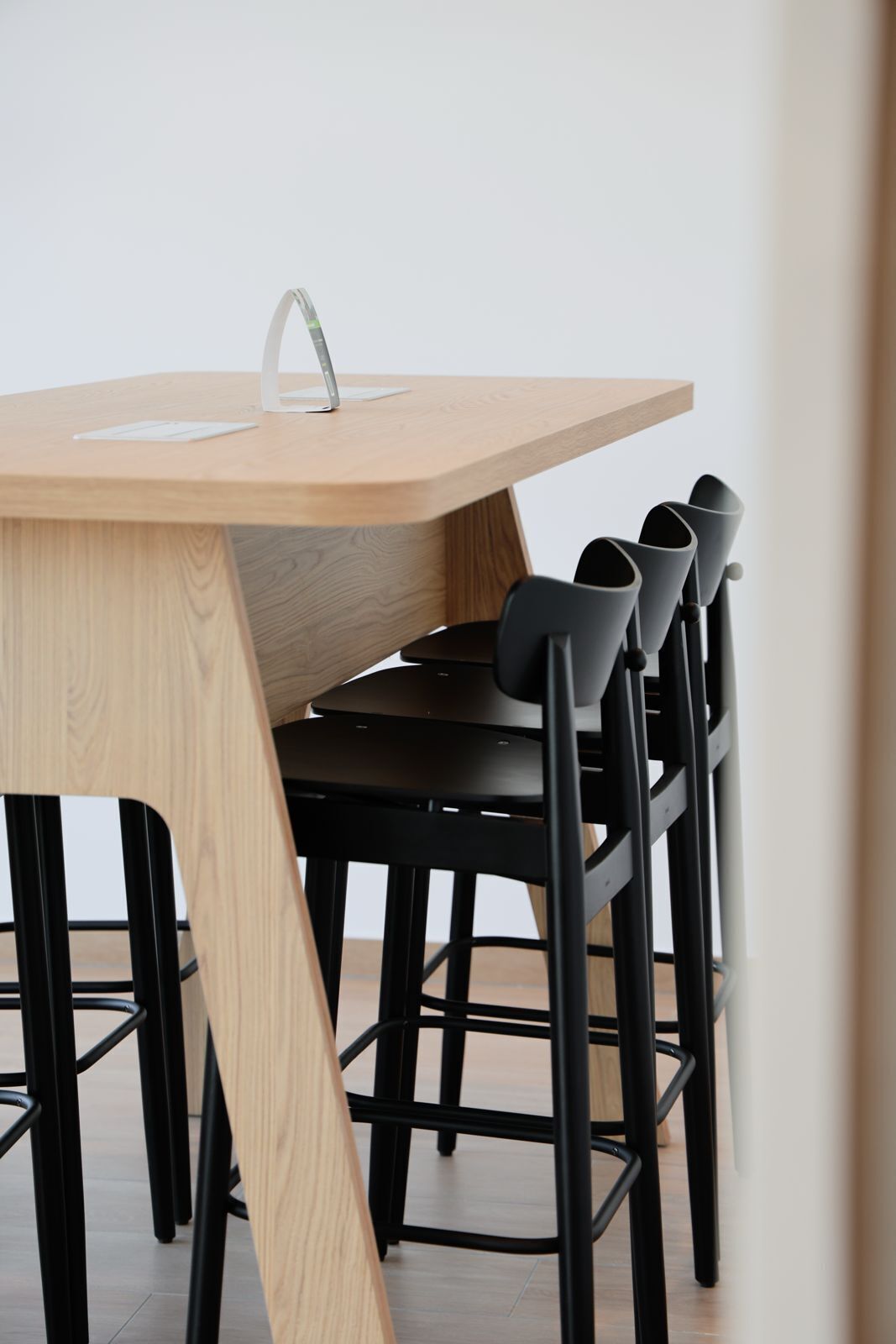 Una mesa de comedor moderna con tapa de madera y sillas negras.