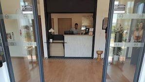 Een hotel receptie met een receptioniste, een receptiebalie en een B&B Hotels logo op de vloermat.