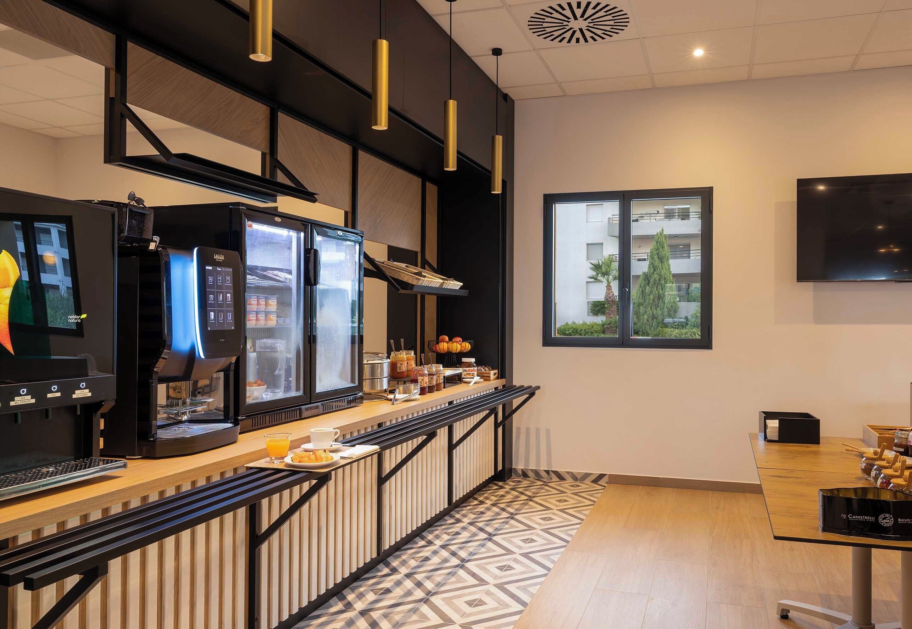 Una cocina moderna con cafetera, refrigerador y ventana con vista a edificios.