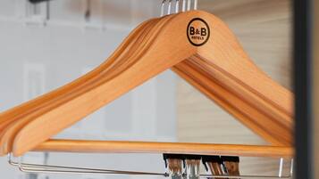 Ein Holzaufhänger mit einem Logo, befestigt an einer Metallstange.