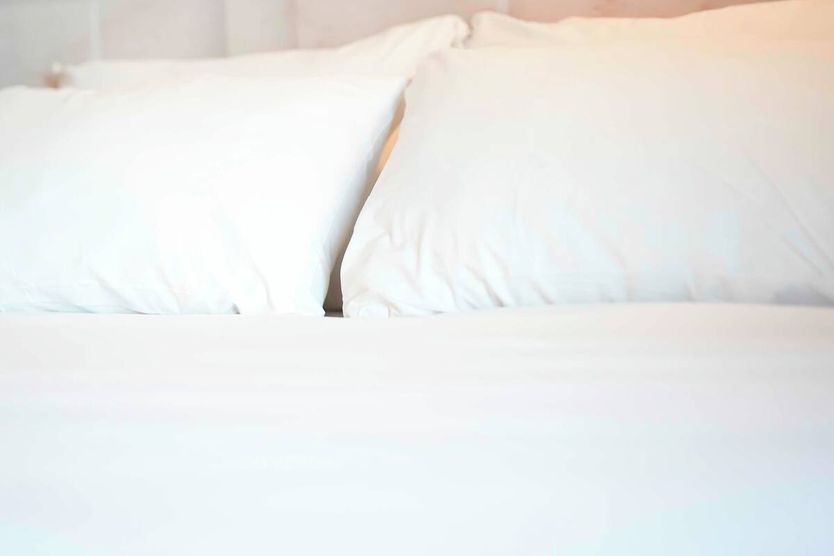 A bed with white bedding and pillows.