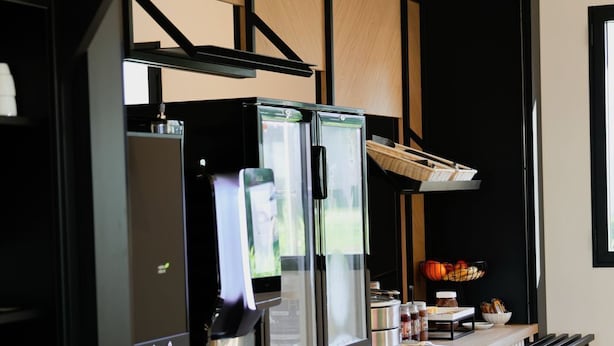 Uma cozinha moderna com geladeira embutida, cafeteira e um pequeno balcão com diversos condimentos e uma cesta.