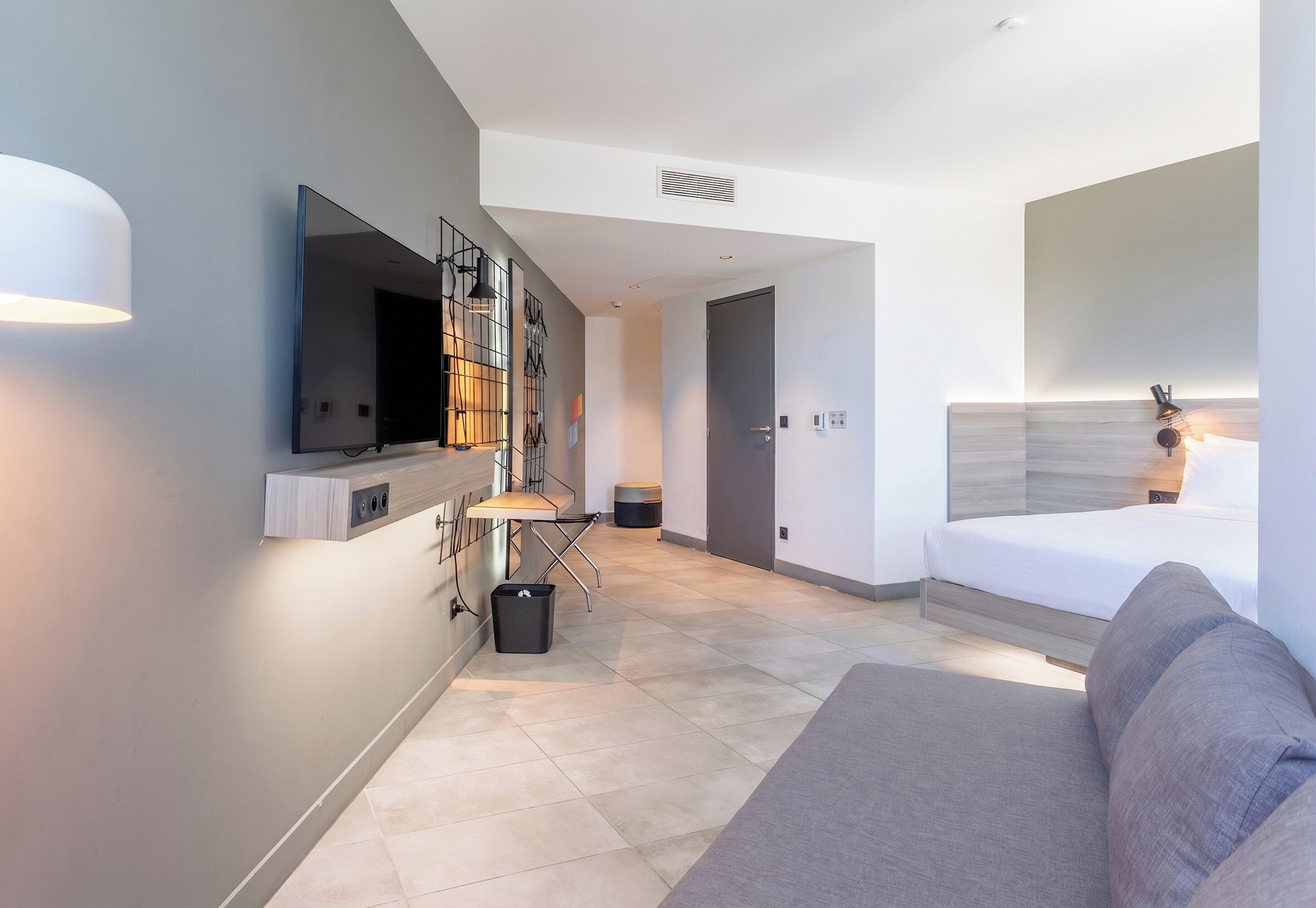 Een moderne hotelkamer met een flatscreen televisie, een bank, een bed en een bureau met stoel.