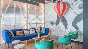 A modern living area with a blue sofa, green chairs, a coffee table, and a wall mural.