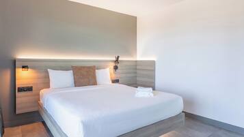 Una habitación de hotel moderna con una cama grande, lámparas de noche y una lámpara fijada a la pared.