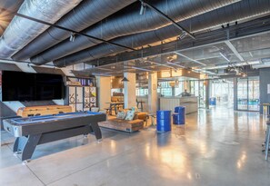 A spacious indoor area with a pool table, seating, and a bar area.