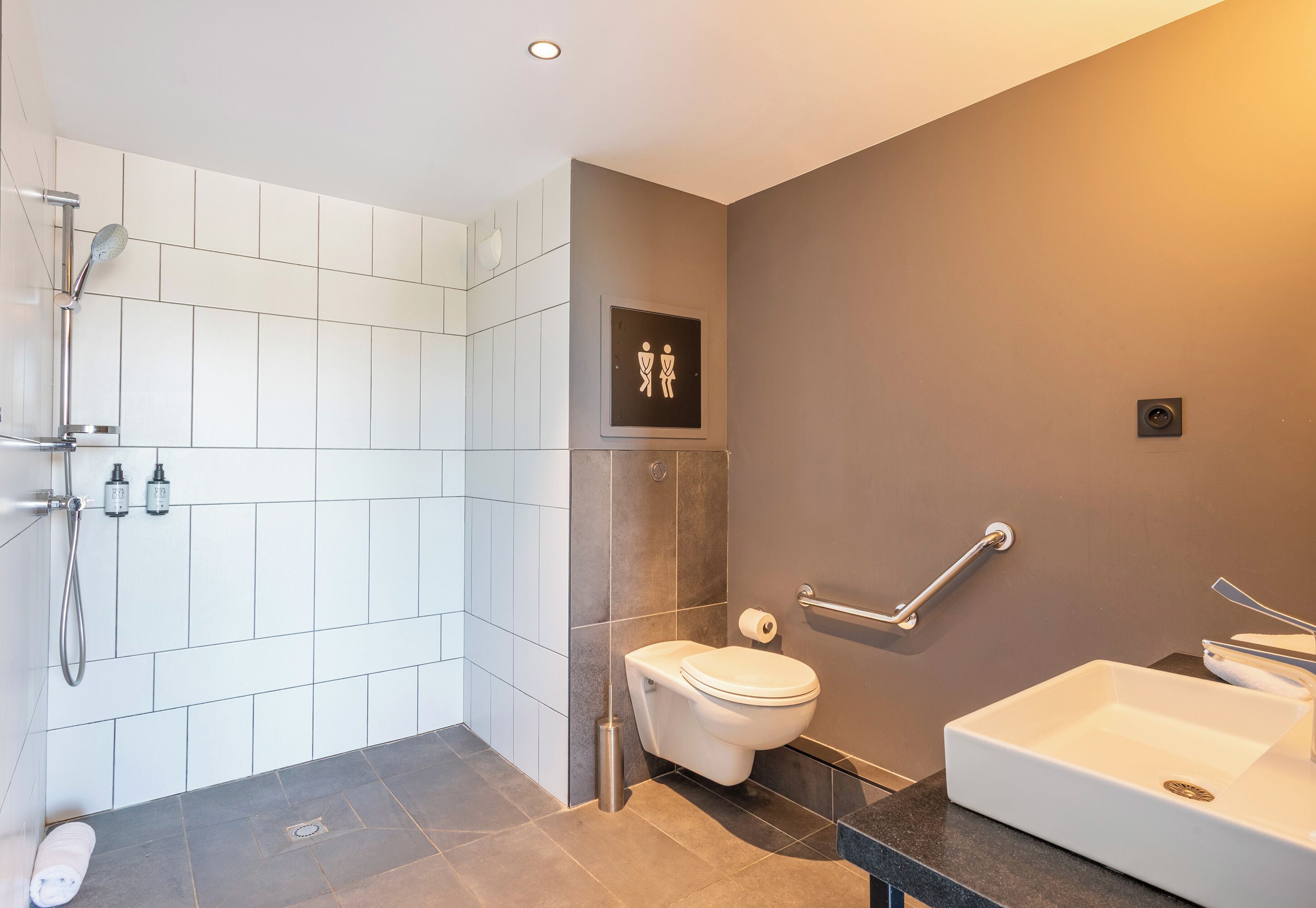 A modern bathroom with a shower, toilet, and sink.