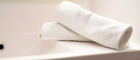A white towel folded on a white sink.