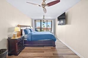 Ein Schlafzimmer mit Bett, Nachttisch, Lampe, Deckenventilator und Blick ins Freie.