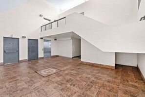 Ein geräumiger Innenraum mit Treppe, mehreren Türen und Fliesenboden.
