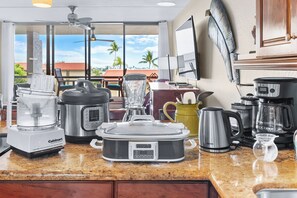 Eine Küche mit einer Kaffeemaschine, einem Mixer und einem Slow Cooker auf der Arbeitsfläche.