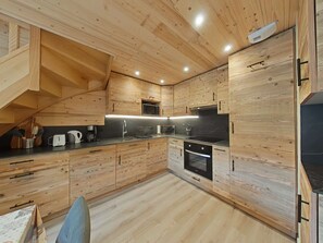 A modern kitchen with wooden cabinetry, a microwave, a stove, and a sink. - Spacious duplex with slope views - 7 guests (Le Grand-Bornand)
