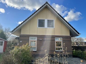 Ein zweistöckiges Haus mit Satteldach, zwei Fenstern im Obergeschoss und einem Klinker-Erdgeschoss.