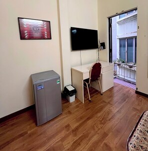 Ein Zimmer mit Schreibtisch, Stuhl, Kühlschrank, Fernseher und einem Balkon mit Blick.