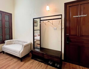 Um quarto com uma poltrona branca, uma porta de madeira e um espelho com moldura de madeira.