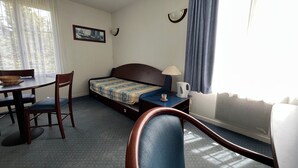 Camera d'albergo con letto, scrivania, sedia, lampada e finestra con tende.