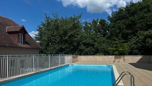 Una piscina rettangolare con recinzione in metallo bianco, circondata da un solarium piastrellato.