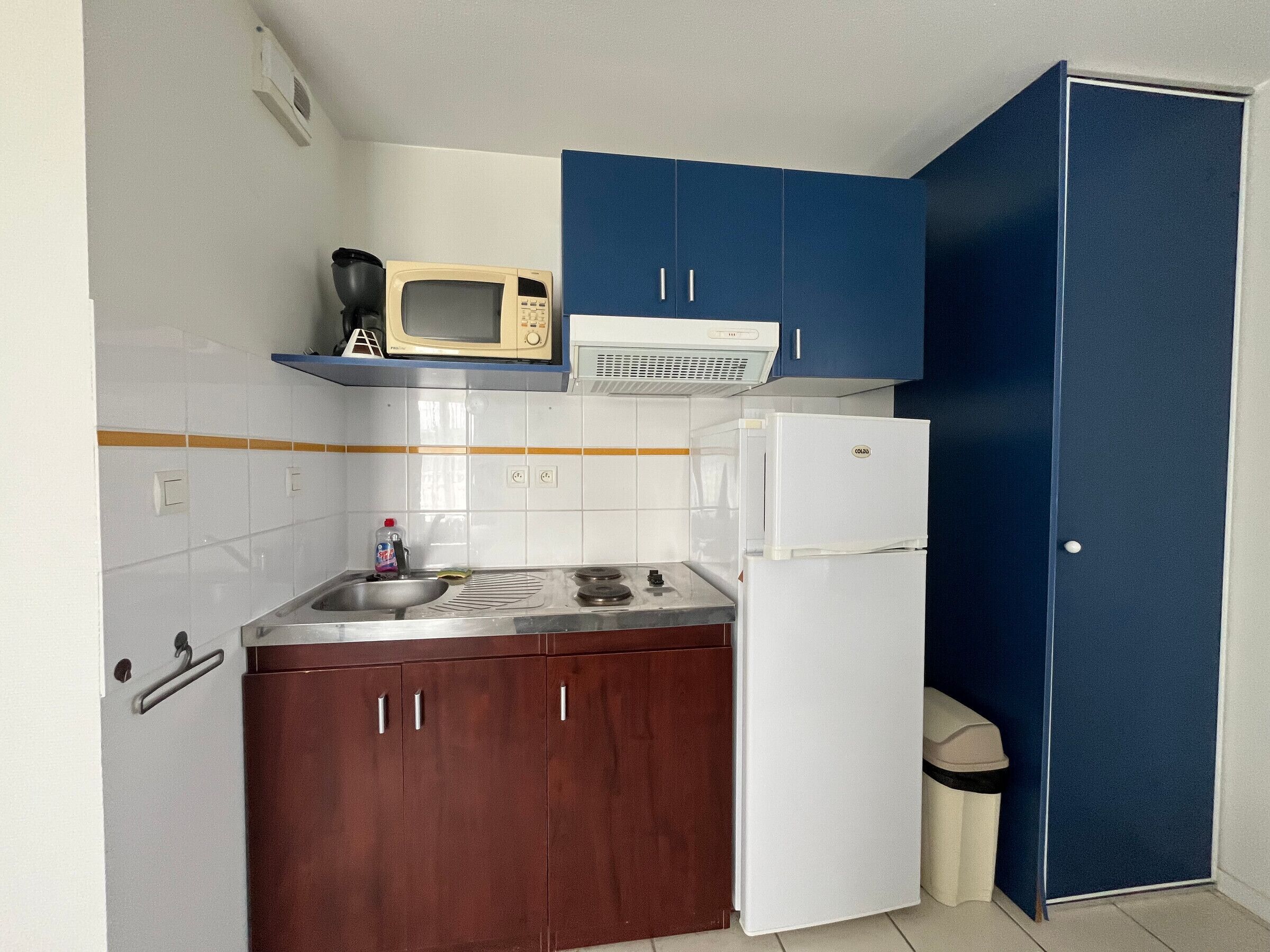 A compact kitchen with a microwave, stove, sink, and a refrigerator.