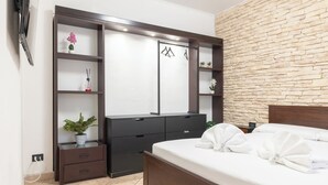 A bedroom with a bed, a wardrobe, a mirror, a TV, and a stone wall. - Apartment via Monte del Gallo (Roma)
