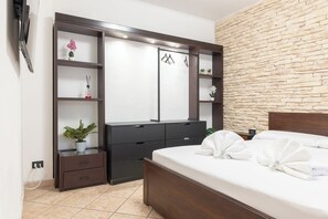Ein Schlafzimmer mit einem Bett, einem Kleiderschrank, einem Spiegel, einem Fernseher und einer Steinwand.