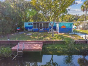 A small house with a dock extending into a pond, surrounded by greenery. - 
CHECK OUT THE RIVER (Spring Hill)