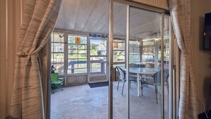 Habitación con puerta corrediza de vidrio que da a un patio exterior con mesa y sillas.