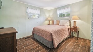Un dormitorio con una cama, dos mesitas de noche con lámparas, un aparador y una ventana con vistas.