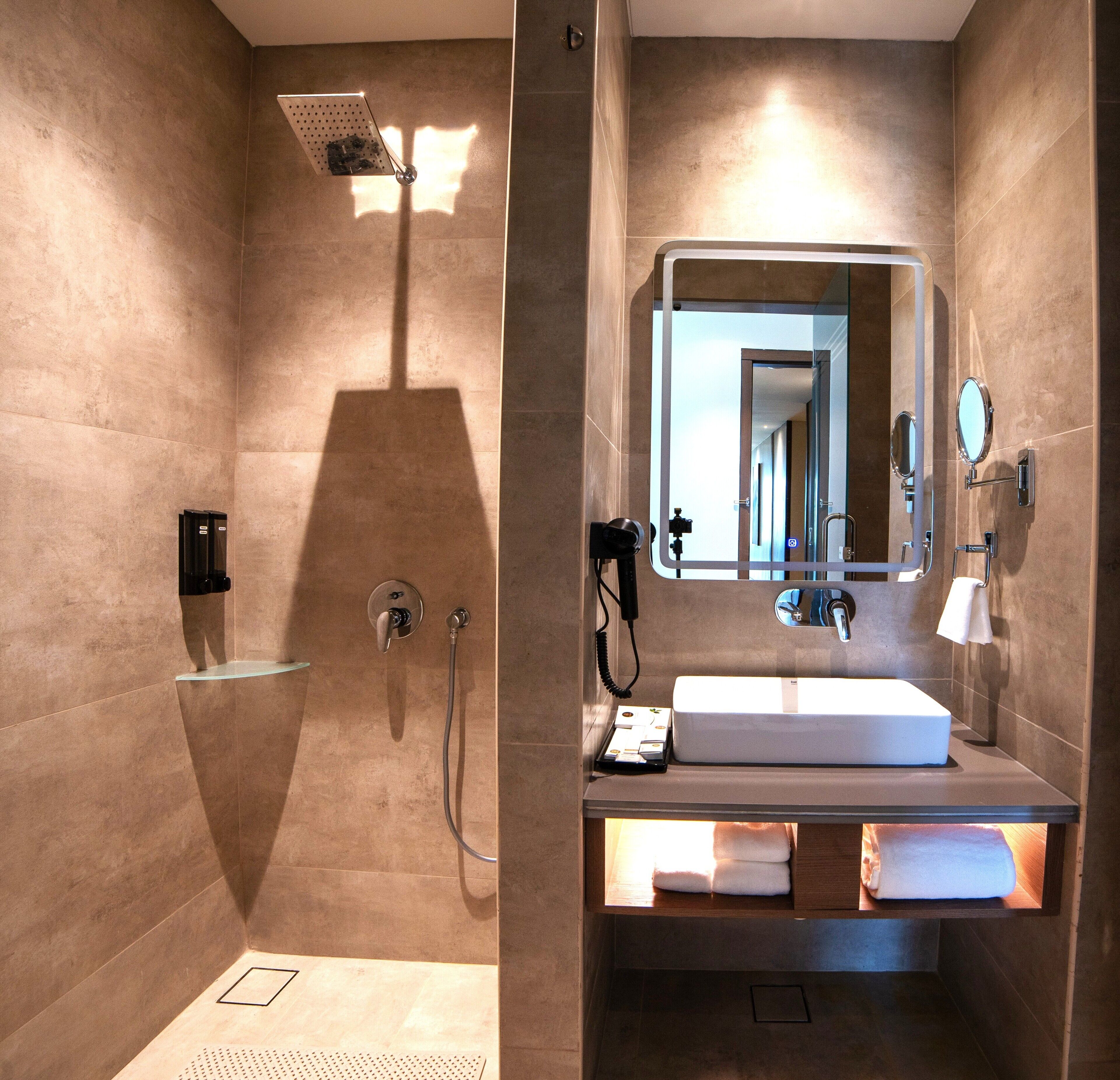 Een moderne badkamer met douche, wastafel en spiegel.