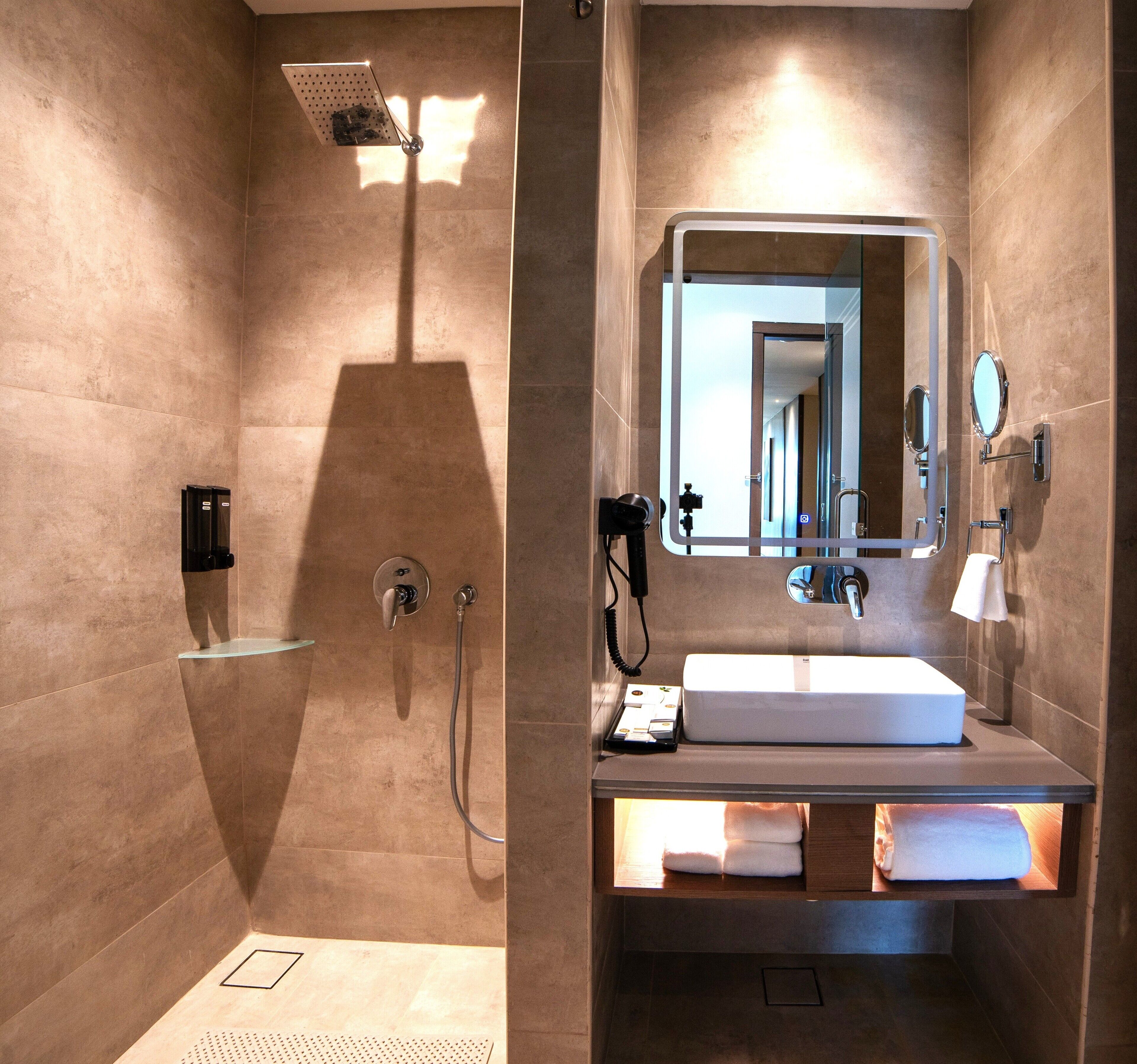 A modern bathroom with a shower, a sink, a mirror, and a towel rack.