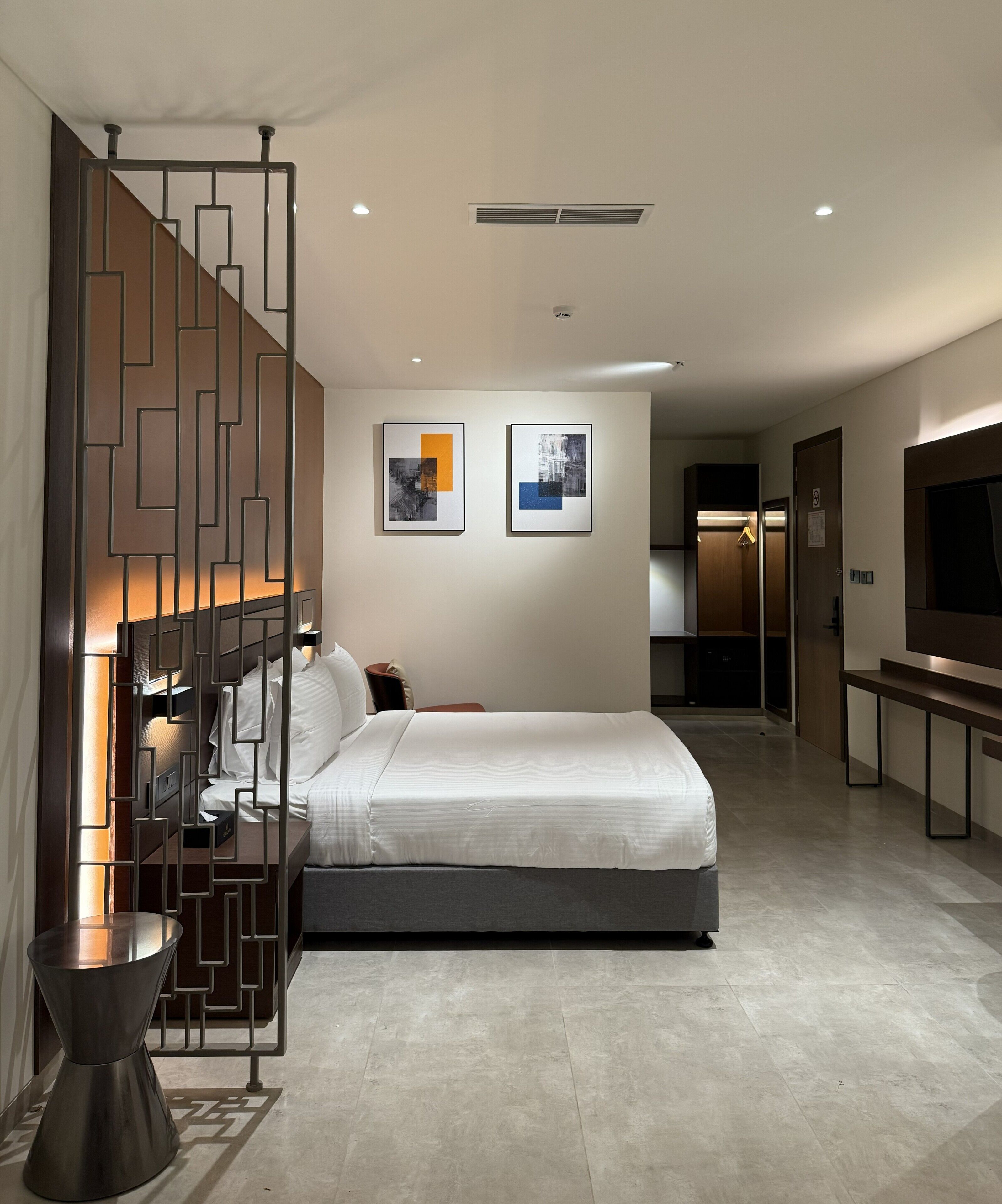 Ein modernes Hotelzimmer mit einem großen Bett, einem Fernseher, einem Schreibtisch und einem begehbaren Kleiderschrank.