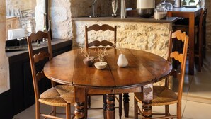 A rustic dining area with a stone wall, wooden table, and chairs. - Historic manor house with a pool, garden, and restaurant. Breathtaking view. (Le Vigan-en-Quercy)