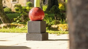 A sculpture with geometric shapes stacked vertically, set against a backdrop of trees and a building. - Historic manor house with a pool, garden, and restaurant. Breathtaking view. (Le Vigan-en-Quercy)