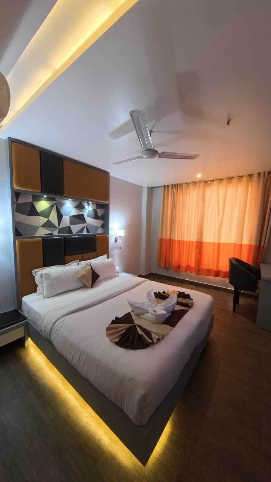 Una habitación de hotel moderna con una cama, un ventilador de techo y una ventana con cortinas.