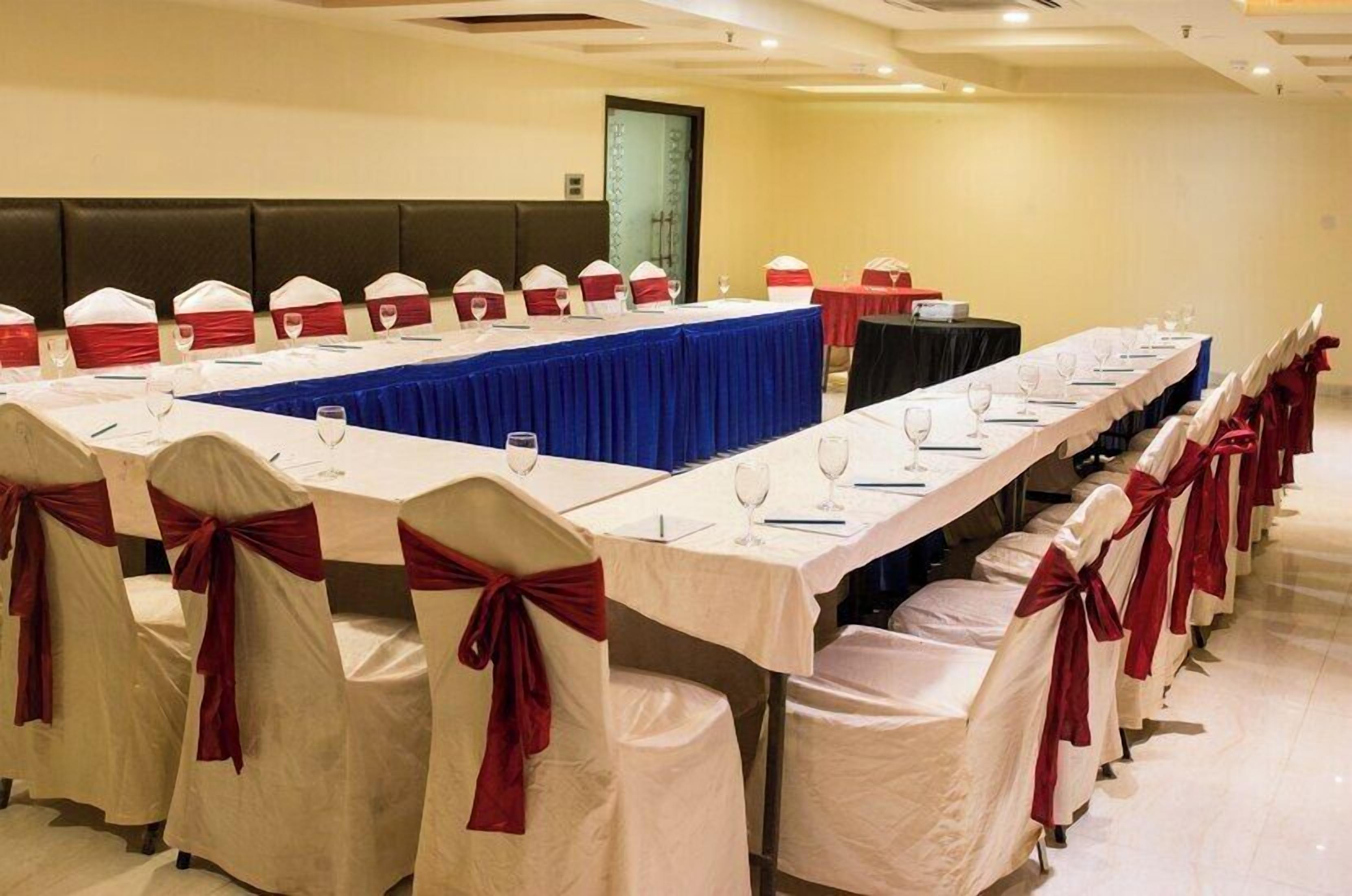 A conference room with long tables, chairs, and a blue tablecloth.