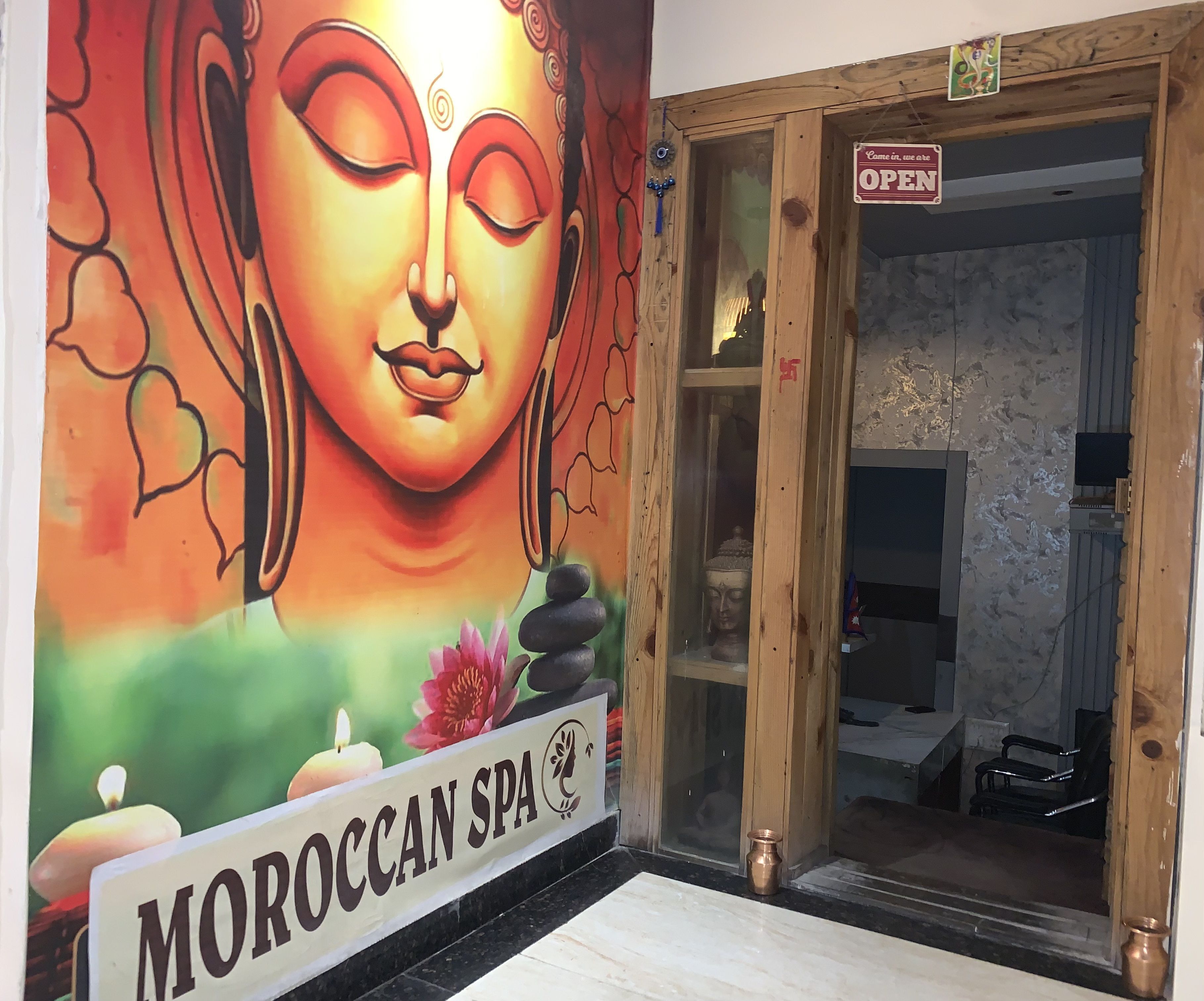 L’entrée d’un spa marocain, avec une fresque représentant un Bouddha, une enseigne et une porte en bois.