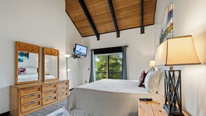 Ein Schlafzimmer mit Bett, Schminktisch, Fernseher und Fenster.