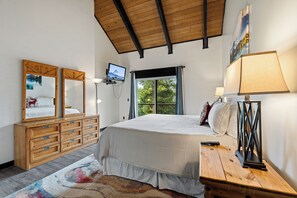 Ein Schlafzimmer mit Bett, Schminktisch, Fernseher und Fenster.