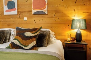 Ein Zimmer mit Holzwänden, einem Bett, einer Lampe und Bildern an der Wand.