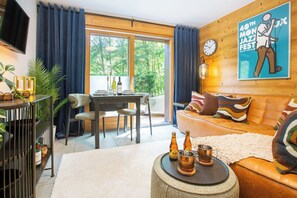 Ein modernes Wohnzimmer mit einer Couch, einem Esstisch und einem an der Wand befestigten Fernseher.
