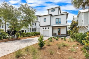 A modern two-story house with a front porch, a driveway, and a landscaped garden. - 5 BR NEW 2026 BUILD | 5 O'Clock Shadow | Gulf Views | Sleeps 12 (Inlet Beach)