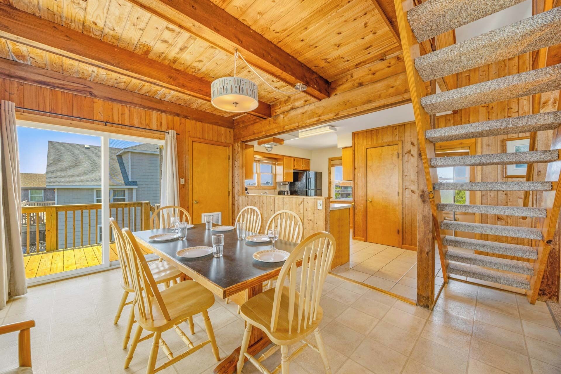 A wooden cabin with a dining area, kitchen, and a staircase.