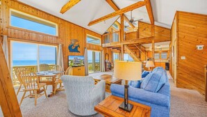 A wooden interior with a dining area, a sofa, a TV, and a staircase leading to an upper level. - Oceanfront, Dog Friendly Home in Avon with Boardwalk to the Beach (Avon)