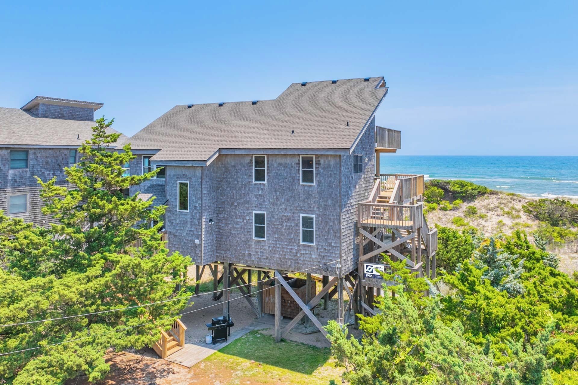 Une maison à deux étages avec une terrasse et vue sur l’océan.