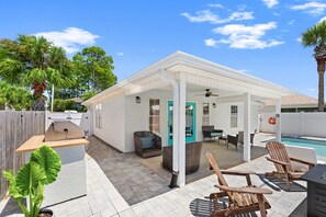 A covered patio area with outdoor furniture, a pool, and a grill. - Paradise Palms! Quiet West End PCB Retreat! Walk to Beach! Sleeps 8! (Panama City Beach)