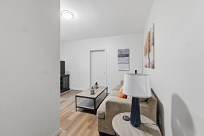 Un salon moderne avec un canapé, une table basse, une lampe et une œuvre d’art accrochée au mur.