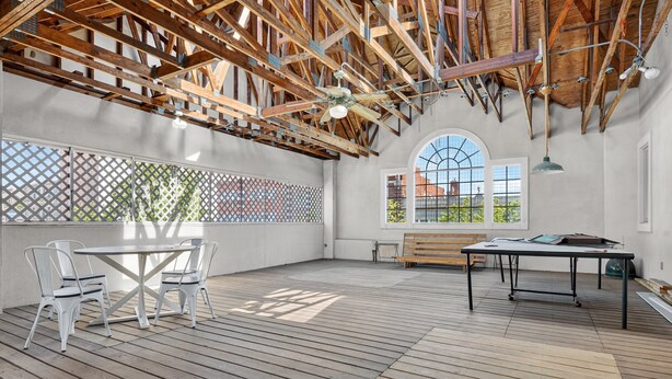 Una terraza abierta con techo de madera, una mesa, sillas y un banco.