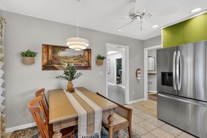 A dining area with a wooden table, chairs, a hanging light fixture, and a painting on the wall. - World Cup 2026 Retreat In The Heart Of Montclair 3 Bedroom Condo (Montclair)