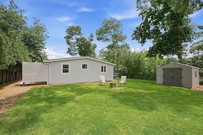 A single-story mobile home with a small deck, a shed, and a well-maintained lawn.